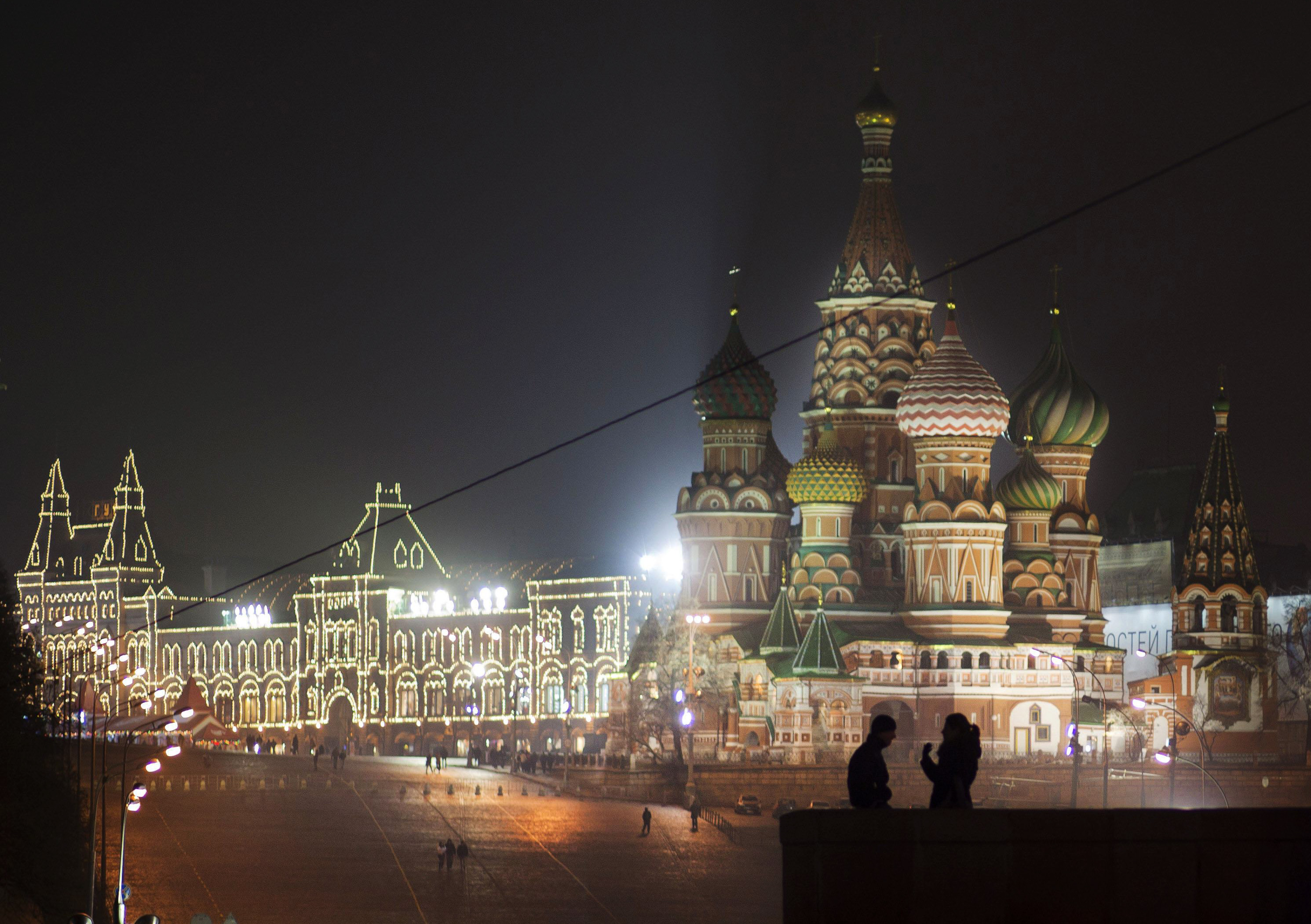 A young couple is seen on a top of the Big Moskvoretsky bridge at the Red Square with St. Basil Cathedral and GUM, the State Department Store, in the background, Moscow, Russia, late Friday, Dec. 2, 2011, . (AP Photo/Alexander Zemlianichenko)