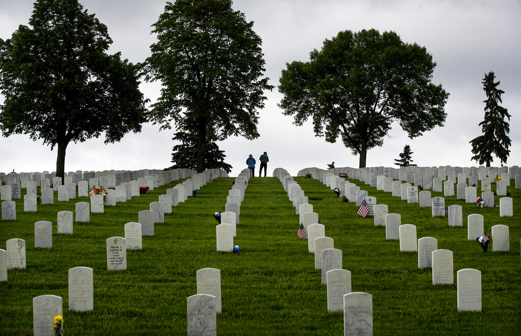People pay their respects at graves of loved ones at Fort Snelling Cemetery on Memorial Day weekend, Sunday May 24, 2020, in Bloomington, Minn. (Jerry Holt/Star Tribune via AP)