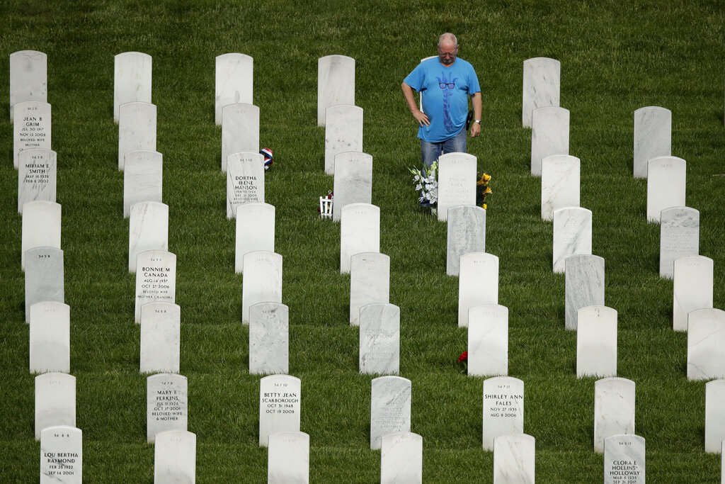 A man pauses at a grave while visiting Leavenworth National Cemetery Saturday, May 23, 2020 in Leavenworth, Kan. Several people said they made their annual visit to the cemetery today instead of Memorial Day to beat the crowd and minimize the chance of catching COVID-19. (AP Photo/Charlie Riedel)