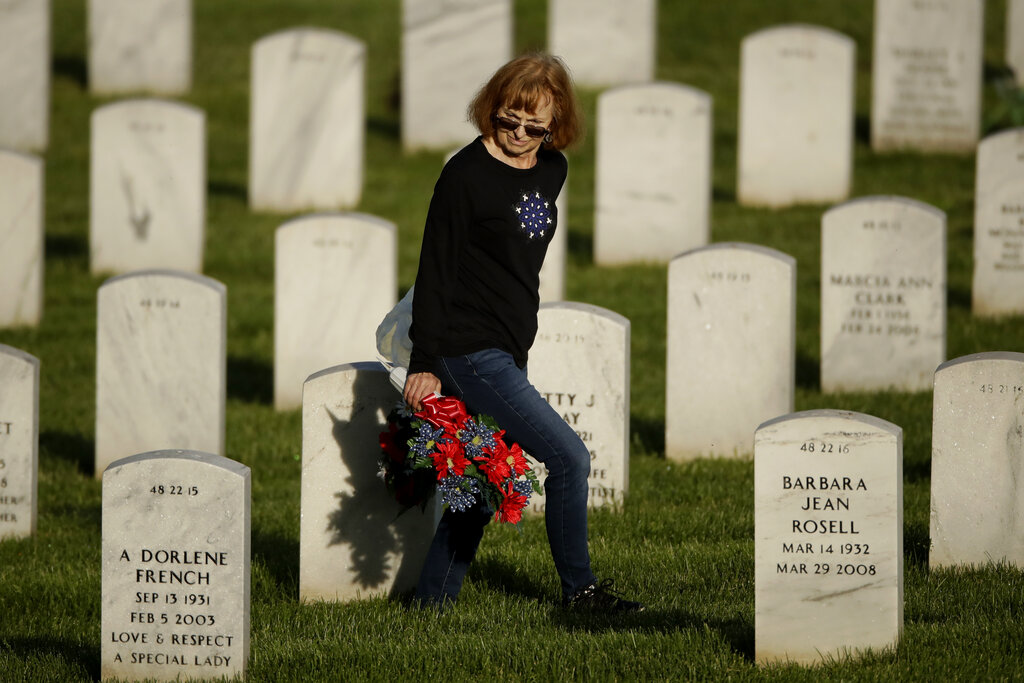 Pam Barba looks for a grave while visiting Leavenworth National Cemetery Saturday, May 23, 2020 in Leavenworth, Kan. Barba said she decided to visit to the cemetery today instead of Memorial Day to beat the crowd and minimize the chance of catching COVID-19. (AP Photo/Charlie Riedel)