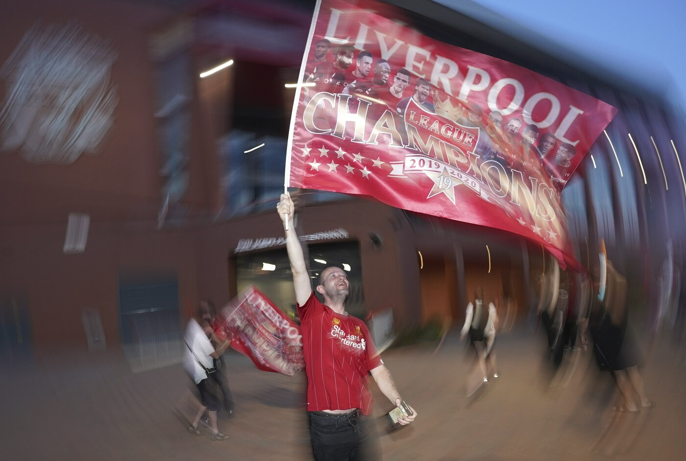 A Liverpool supporter celebrates outside Anfield Stadium in Liverpool, England, Thursday, June 25, 2020 after hearing Chelsea had scored in the English Premier League soccer match between Chelsea and Manchester City. Liverpool will be crowned Premier League champions if Manchester City fail to beat Chelsea. (AP Photo/Jon Super)