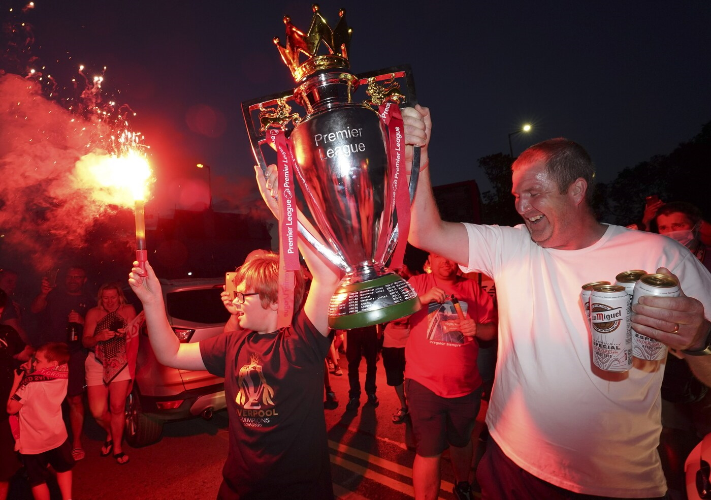 Liverpool supporters hold a replica Premier League trophy as they celebrate outside of Anfield Stadium in Liverpool, England, Thursday, June 25, 2020 after Liverpool clinched the English Premier League title. Liverpool took the title after Manchester City failed to beat Chelsea on Wednesday evening. (AP photo/Jon Super)