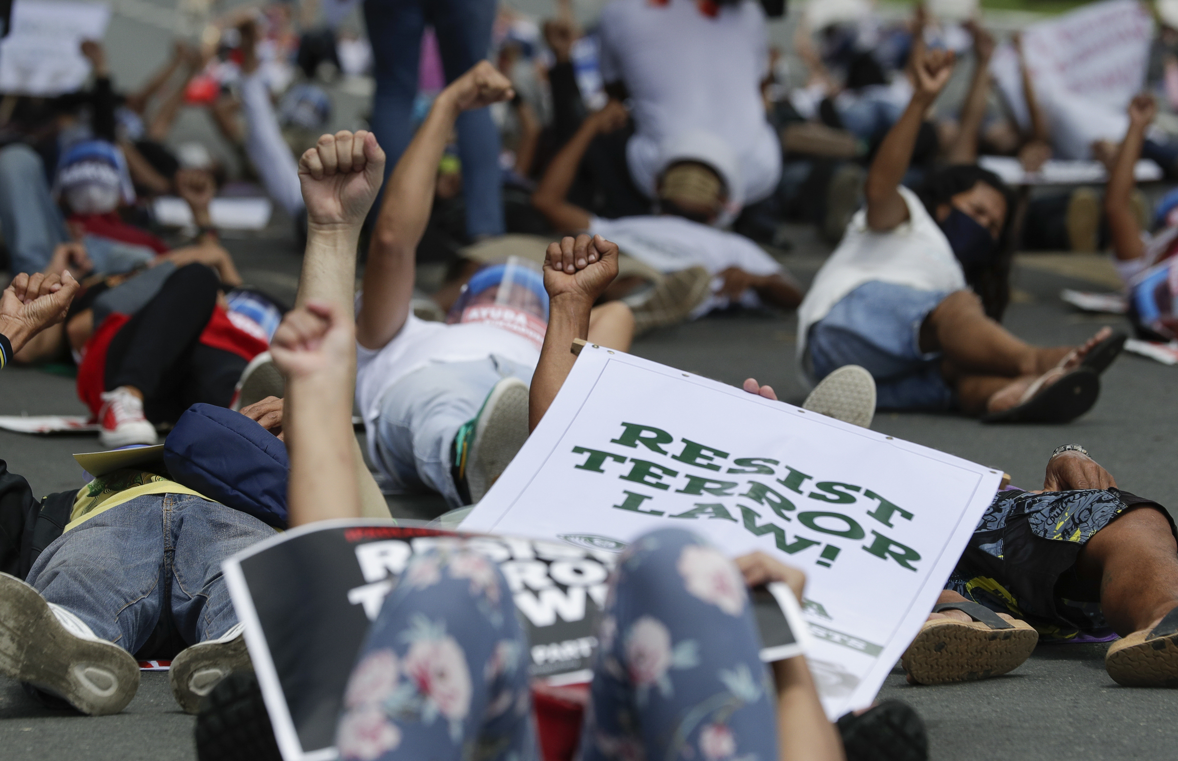 Protesters raise their clenched fists as they lay on the streets during a rally against the anti-terror law at the University of the Philippines in Manila, Philippines on Tuesday July 7, 2020. Philippine President Rodrigo Duterte recently signed a widely opposed anti-terror law which critics fear could be used against human rights defenders and to muzzle dissent. (AP Photo/Aaron Favila)