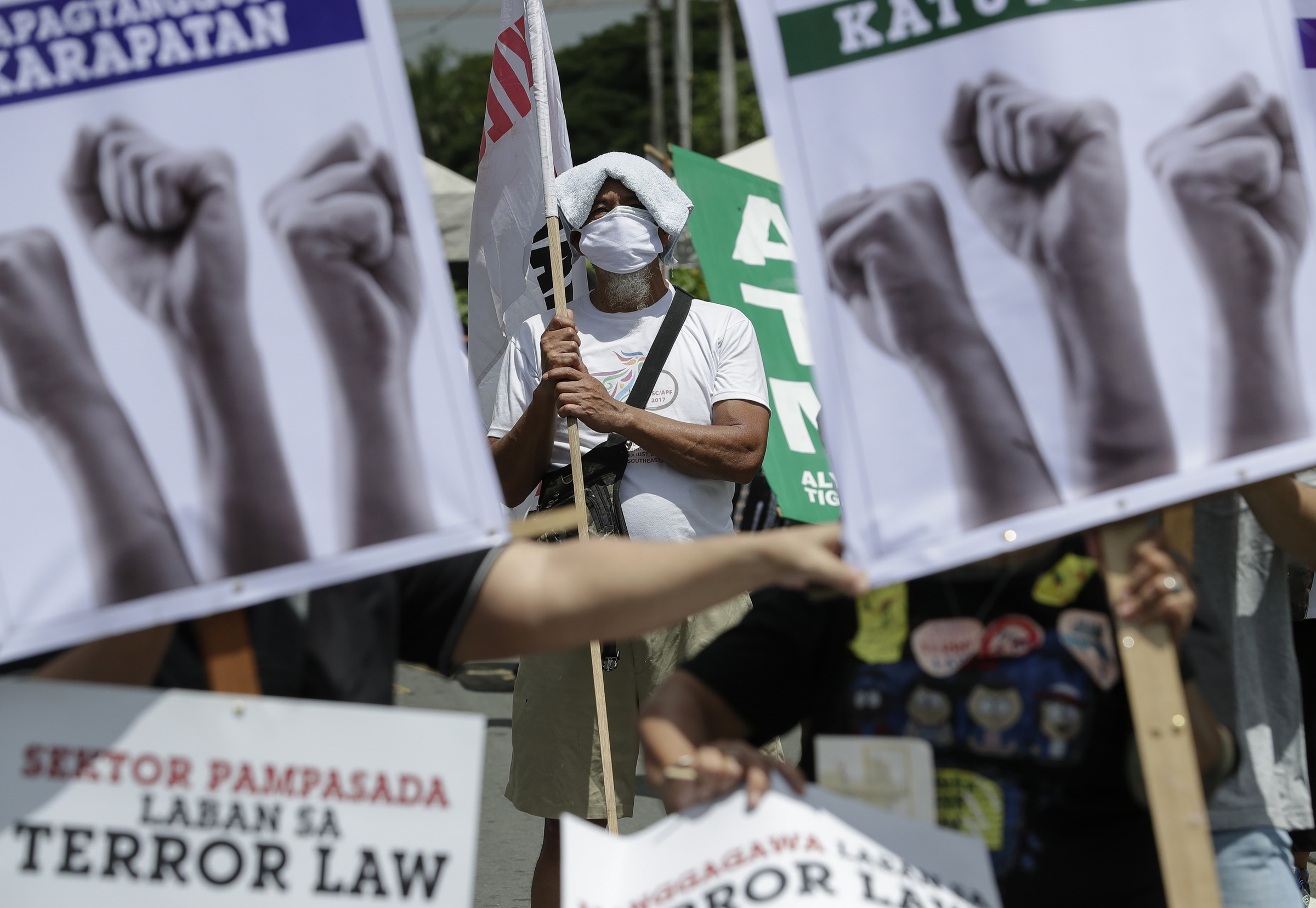 A man stands beside slogans during a rally against the anti-terror law at the University of the Philippines in Manila, Philippines on Tuesday July 7, 2020. Philippine President Rodrigo Duterte recently signed a widely opposed anti-terror law which critics fear could be used against human rights defenders and to muzzle dissent. (AP Photo/Aaron Favila)