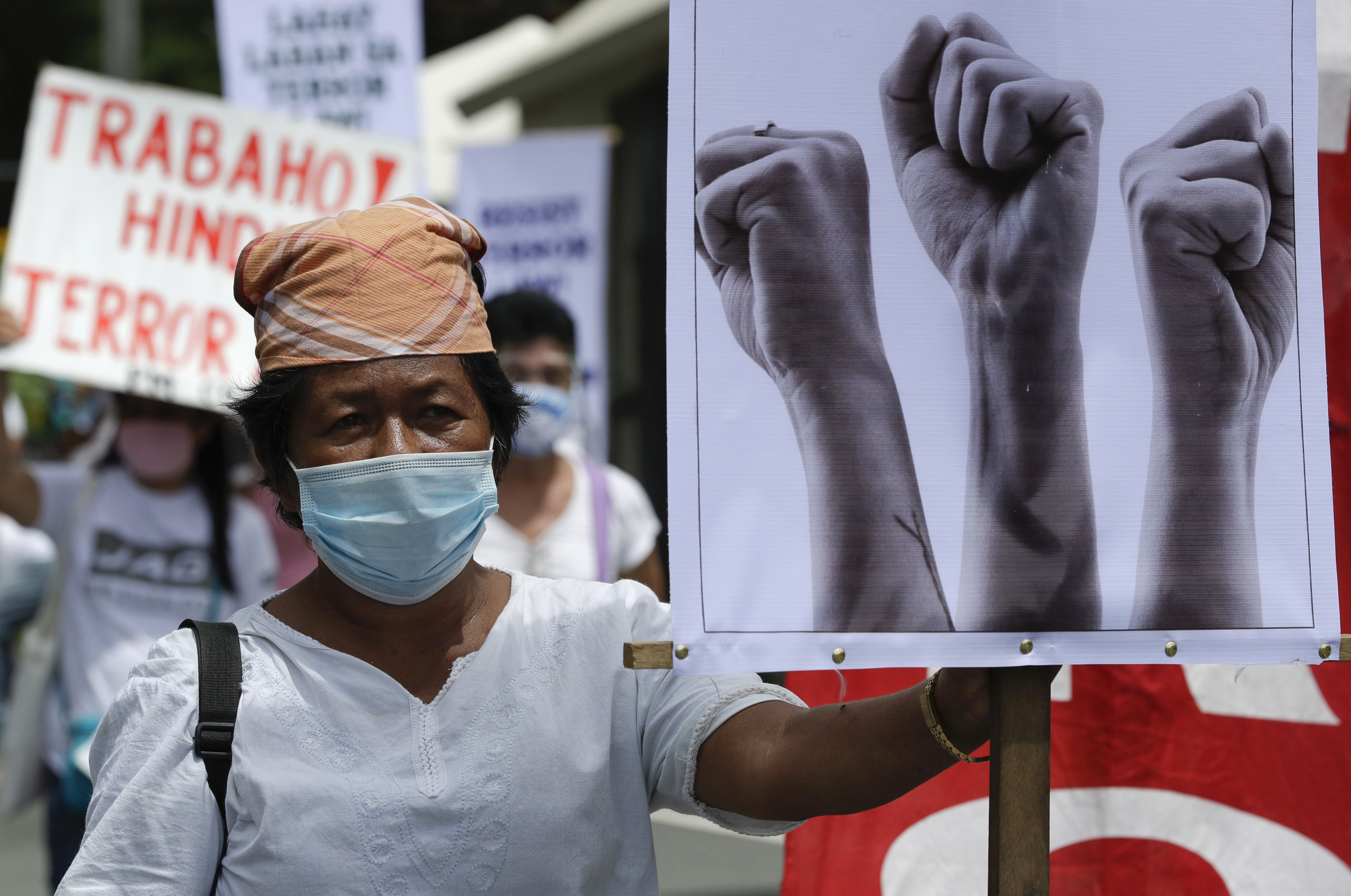 A woman stands beside slogans during a rally against the anti-terror law at the University of the Philippines in Manila, Philippines on Tuesday, July 7, 2020. Philippine President Rodrigo Duterte recently signed a widely opposed anti-terror law which critics fear could be used against human rights defenders and to muzzle dissent. (AP Photo/Aaron Favila)