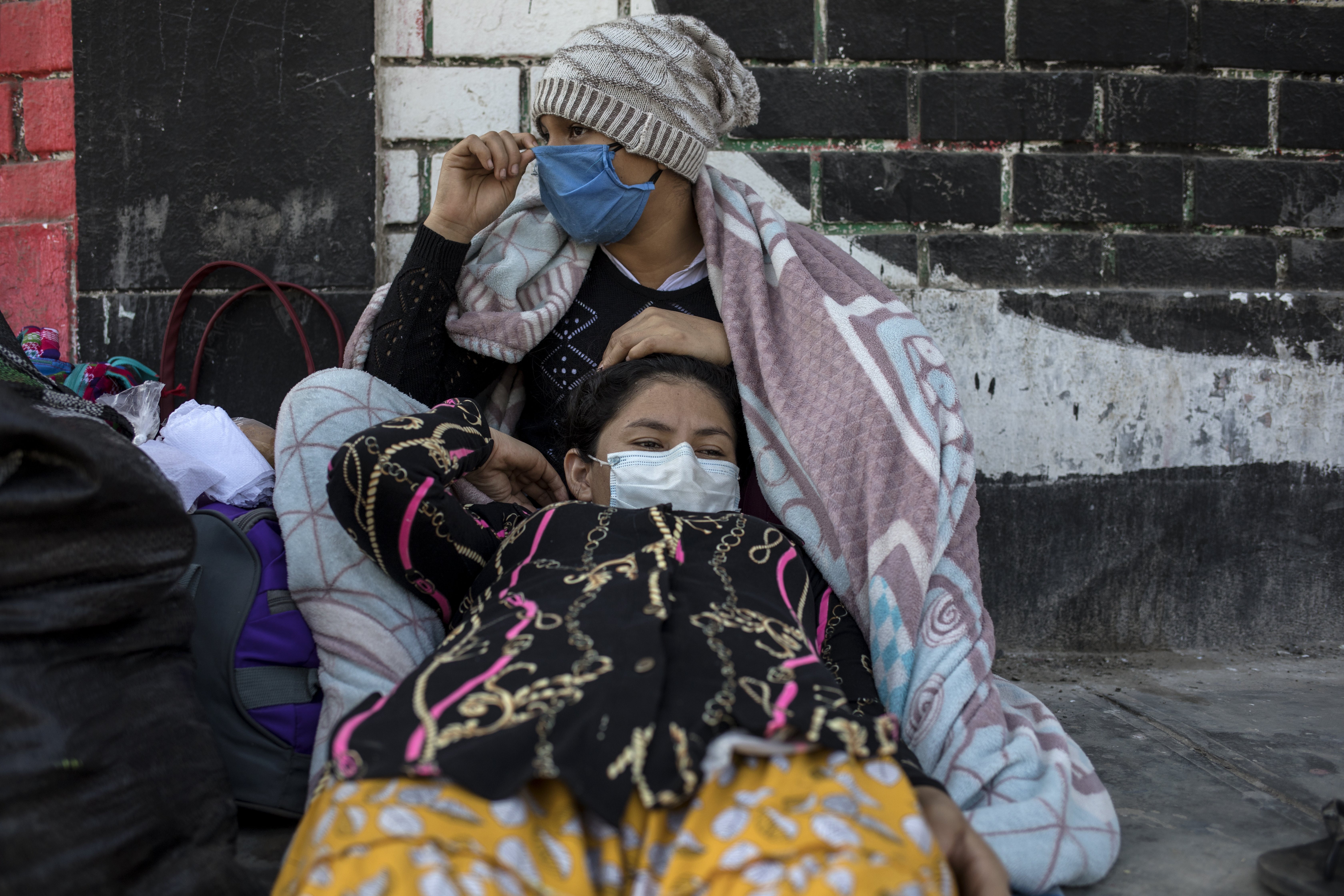 Milka Segura, 15, rests with her sister Ruth, 20, in a makeshift camp on the side of a highway, Tuesday, April 21, 2020, in Lima, Peru. After not being allowed to leave the capital because the strict quarantine rules amid the new coronavirus pandemic, day laborers and informal workers are now allowed to travel home. (AP Photo/Rodrigo Abd)