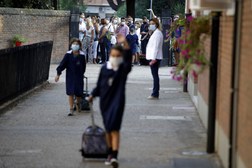 Relatives and parents look at students entering the San Policarpo parish as Italian schools reopened, in Rome, Monday, Sept. 14, 2020. Primary school 