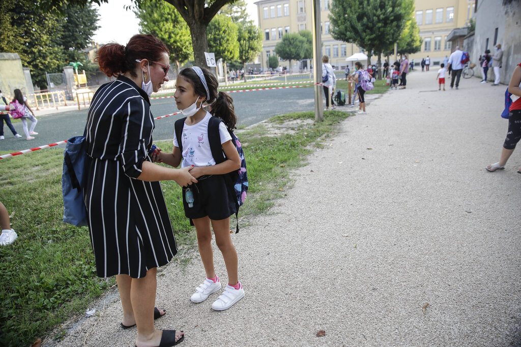 Maria Cristina Baggi greets her ten-year-old daughter Cecilia Rungi outside the San Biagio primary school in Codogno, Italy, Monday, Sept. 14, 2020. The morning bell Monday marks the first entrance to the classroom for the children of Codogno since Feb. 21,  when panicked parents were sent to pick up their children after the northern Italian town gained notoriety as the first in the West to record local transmission of the coronavirus. (AP Photo/Luca Bruno)