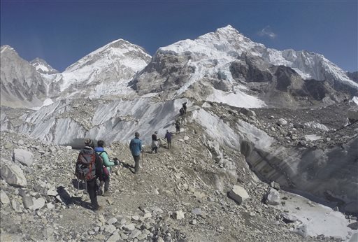 FILE - In this Feb. 22, 2016 file photo, international trekkers pass through a glacier at the Mount Everest base camp, Nepal. Nearly 300 people have died on Mt. Everest in the century or so since climbers have been trying to reach its summit. At least 100 of them are still on the mountain, perhaps 200. (AP Photo/Tashi Sherpa, file)
