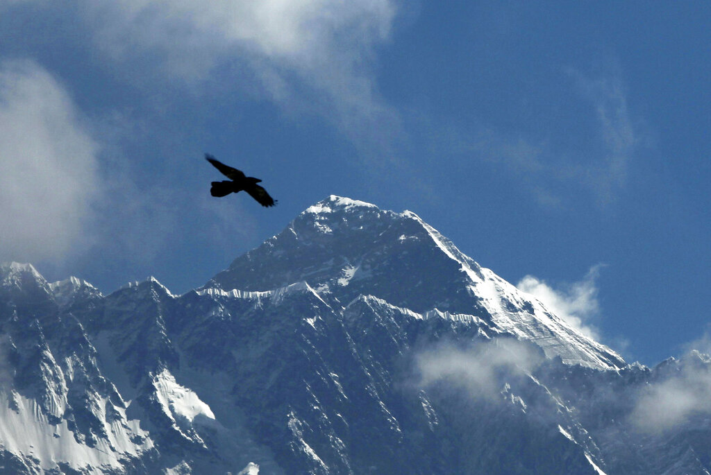 FILE - In this Monday, May 27, 2019, file photo, a Bird flies in the backdrop of Mount Everest, as seen from Namche Bajar, Solukhumbu district, Nepal. Four experienced Sherpa guides are attempting to climb to the top of Mount Everest in less than a week during the final days of winter to set a new climbing record on the world's highest peak. The team is flying on a helicopter to the Everest base camp on Monday, Feb. 24 and will begin the ascent on Tuesday. (AP Photo/Niranjan Shrestha, File)