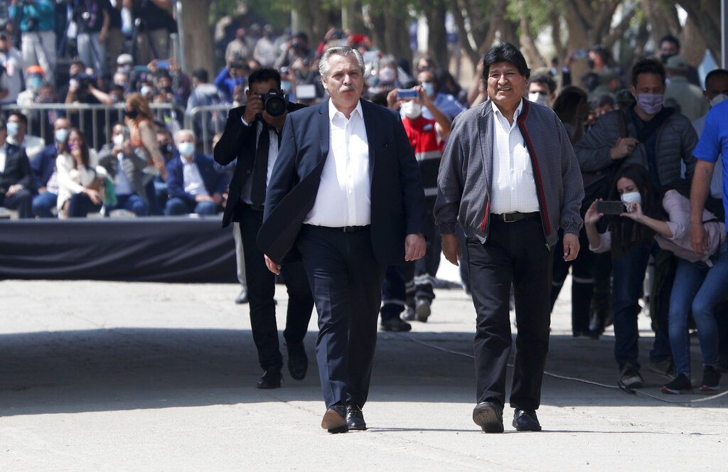 Argentina's President Alberto Fernandez, front left, walks with Bolivia's former President Evo Morales as they cross the bridge connecting the town of La Quiaca, Argentina with the town of Villazon, Bolivia, Monday, Nov. 9, 2020. Morales, who fled into exile after resigning last November, returned to his homeland the day after the presidential inauguration of his former finance minister Luis Arce. (AP Photo/Juan Karita)