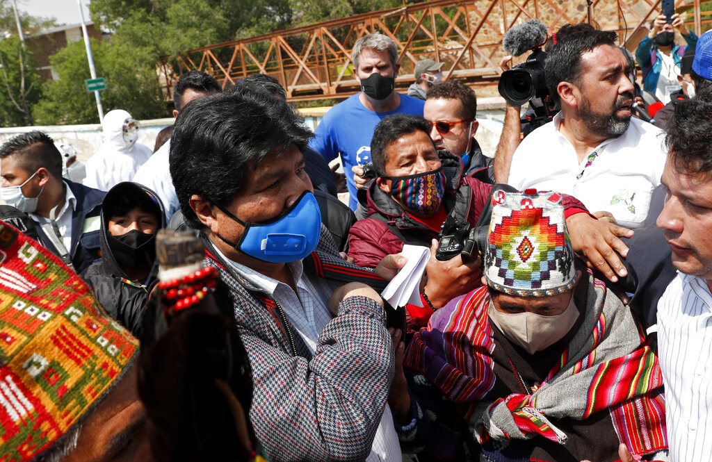 Bolivia's former President Evo Morales, center left wearing a mask amid the COVID-19 pandemic, is greeted by supporters in Villazon, Bolivia, Monday, Nov. 9, 2020, after he walked across a border bridge from Argentina. Morales, who fled into exile after resigning last November, returned to his homeland the day after the presidential inauguration of his former finance minister Luis Arce. (AP Photo/Juan Karita)