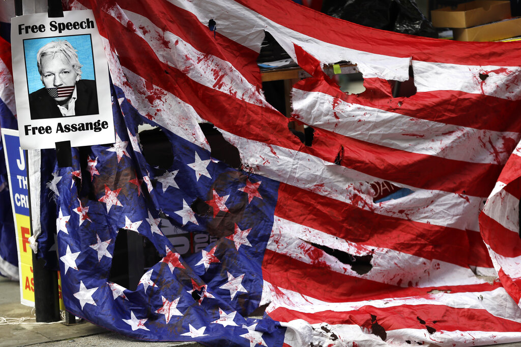 A Free Assange banner and a blood spattered US flag are tied opposite the Old Bailey in London, Thursday, Oct. 1, 2020, as the Julian Assange extradition hearing to the US continues. (AP Photo/Kirsty Wigglesworth)