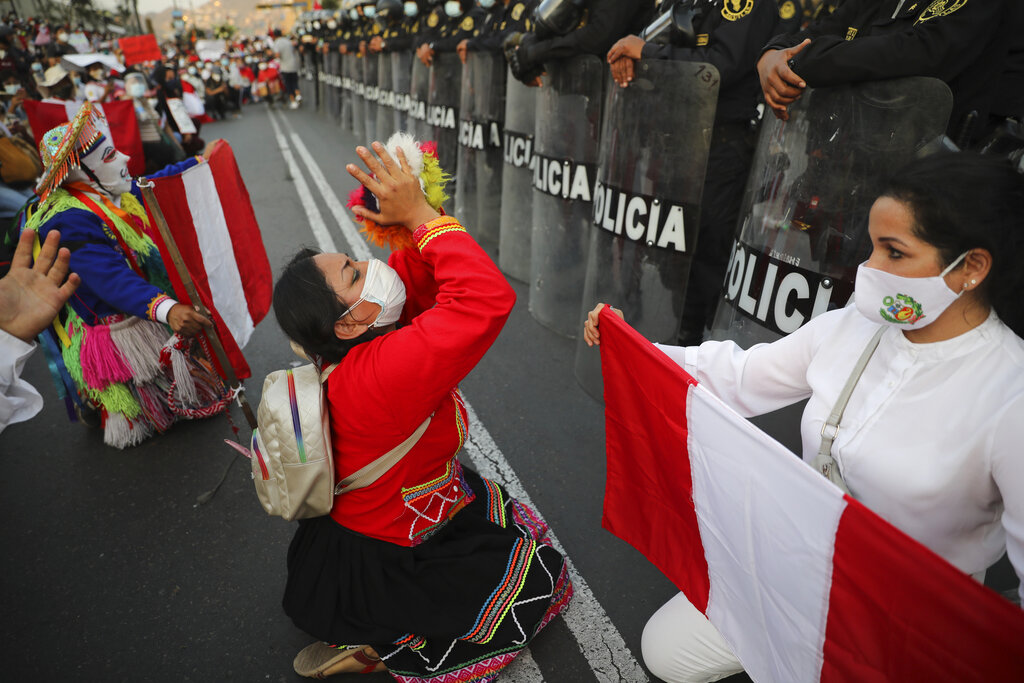 Local folk artists perform next to a police line outside the Congress building, as they wait for news from inside on who will be the country's next president, in Lima, Peru, Sunday, Nov. 15, 2020. Interim President Manuel Merino announced his resignation following massive protests unleashed when lawmakers ousted President Martin Vizcarra. (AP Photo/Rodrigo Abd)