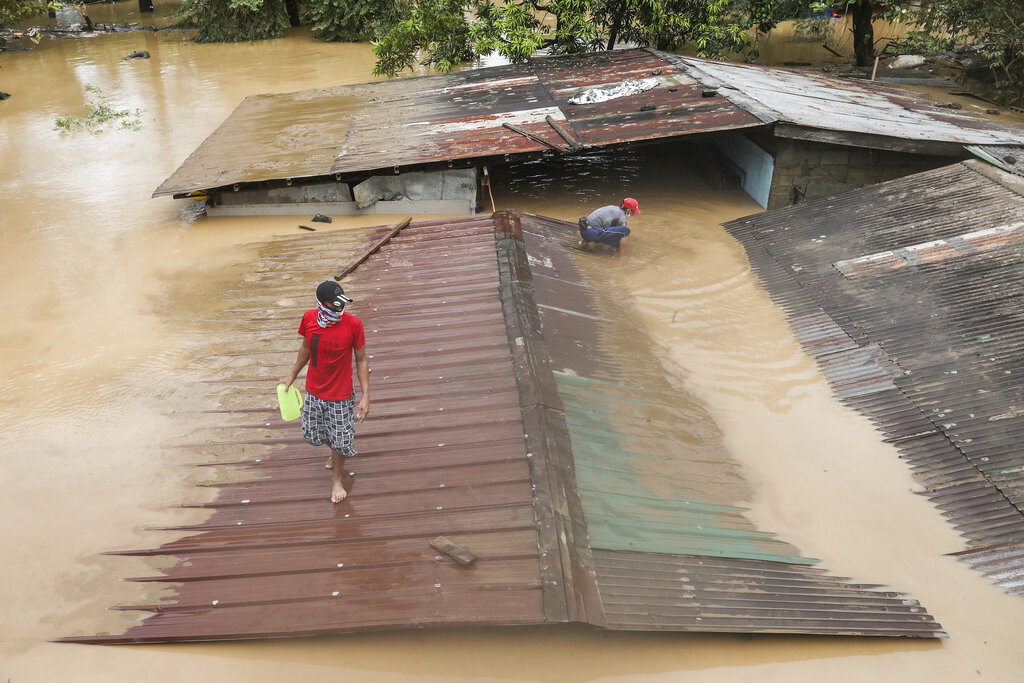 A man walks on top of a roof of a submerged house as floods inundate villages due to Typhoon Vamco in Rizal province, Philippines on Thursday Nov. 12, 2020. The typhoon swelled rivers and flooded low-lying areas as it passed over the storm-battered northeast Philippines, where rescuers were deployed early Thursday to help people flee the rising waters. (AP Photo/Basilio Sepe)