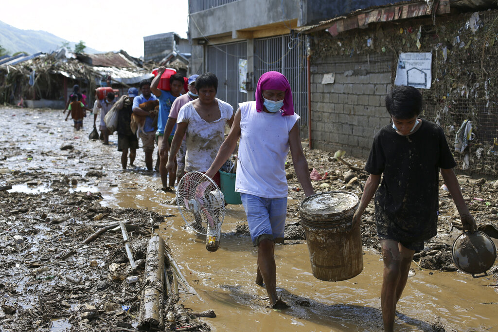 Residents retrieve belongings from their homes at the typhoon-damaged Kasiglahan village in Rodriguez, Rizal province, Philippines, Friday, Nov. 13, 2020. Thick mud and debris coated many villages around the Philippine capital Friday after Typhoon Vamco caused extensive flooding that sent residents fleeing to their roofs and killing dozens of people. (AP Photo/Aaron Favila)