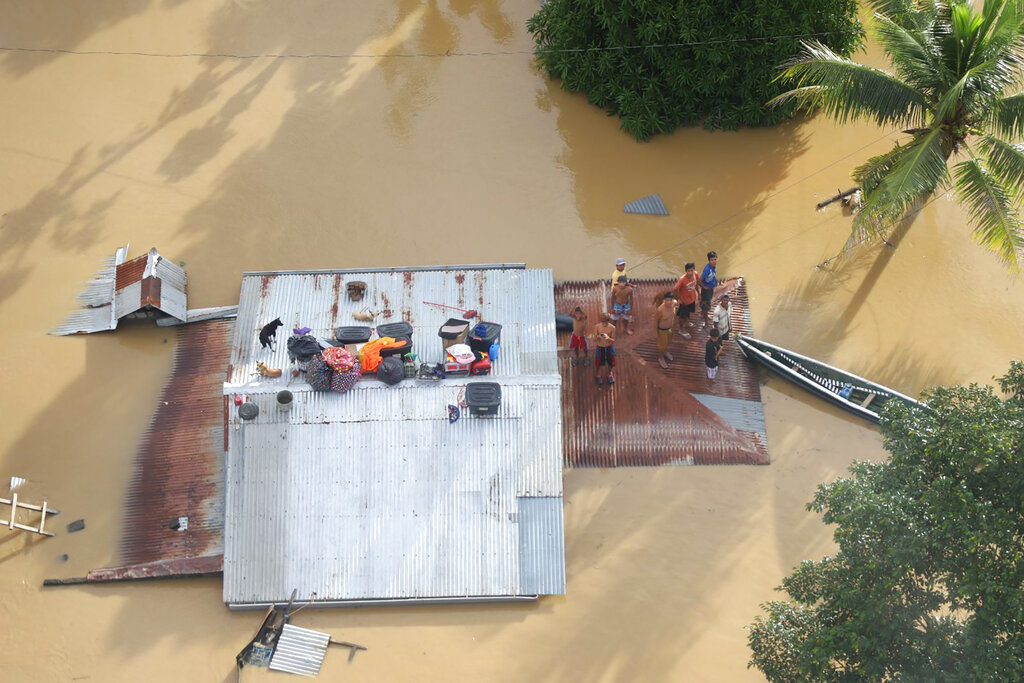 In this photo provided by the Philippine Coast Guard, residents stay on the roof of their homes as they are surrounded by floods in Cagayan valley region, northern Philippines Saturday, Nov. 14, 2020. Thick mud and debris coated many villages around the Philippine capital Friday after Typhoon Vamco caused extensive flooding that sent residents fleeing to their roofs and killing dozens of people. (Philippine Coast Guard via AP)