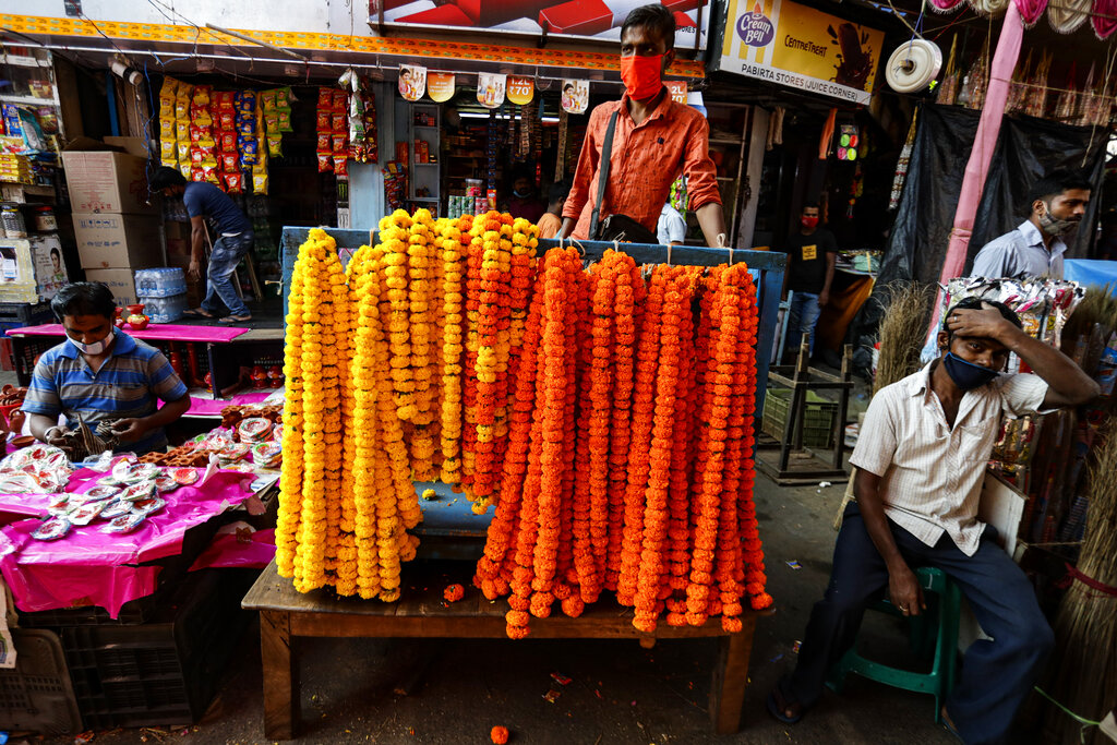 A vendor wearing a face mask as a precautionary measure against the coronavirus sells marigold garlands used to perform rituals during Diwali, the Hindu festival of lights, on a street in Kolkata, India, Saturday, Nov. 14, 2020. Diwali is one of Hinduism's most important festivals, dedicated to the worship of the goddess of wealth Lakshmi. (AP Photo/Bikas Das)