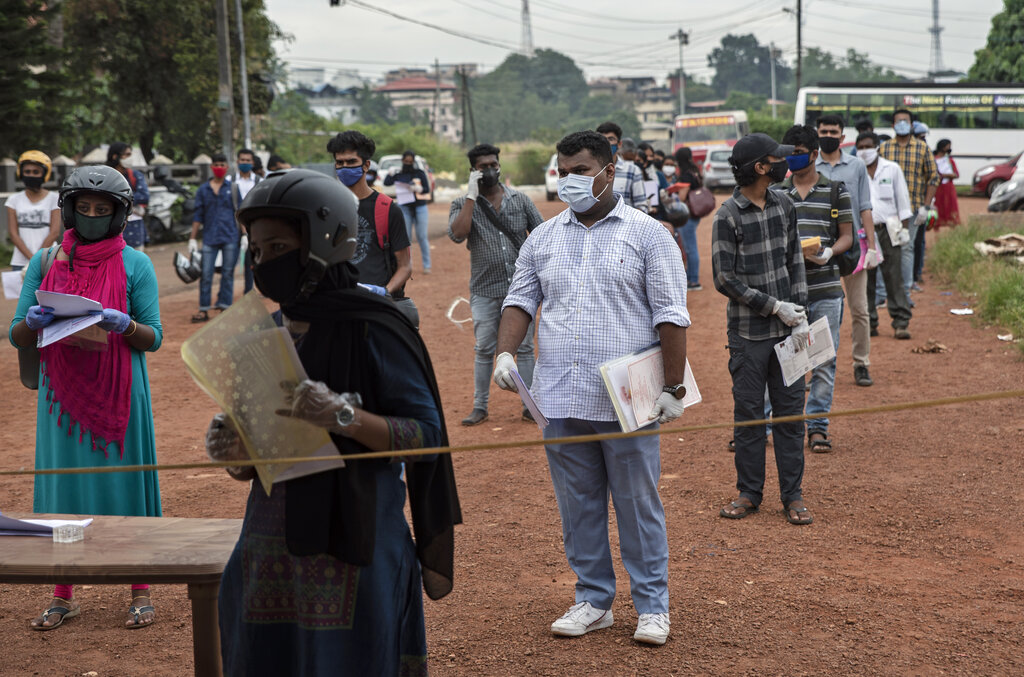 Applicants wearing masks and gloves as a precaution against COVID-19 keep physical distancing as they line up for a driving test in Kochi, Kerala state, India, Monday, Nov.16, 2020. A country of nearly 1.4 billion people, India is the world's second most coronavirus affected country after the United States. (AP Photo/R S Iyer)