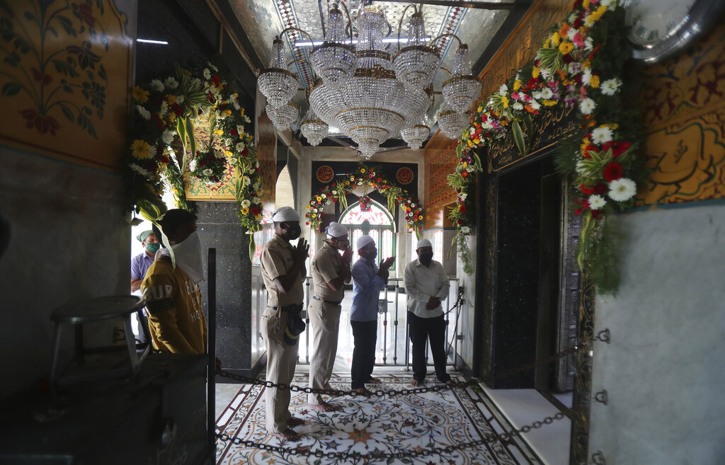 Police officers along with devotees offer prayers at the shrine of Makhdoom Ali Mahimi, an ancient Muslim scholar and saint in Mumbai, India, Monday, Nov. 16, 2020. Religious places across the Maharashtra state reopened for devotees on Monday after remaining closed due to the COVID-19 pandemic. A country of nearly 1.4 billion people, India is the world's second most coronavirus affected country after the United States.(AP Photo/Rafiq Maqbool)