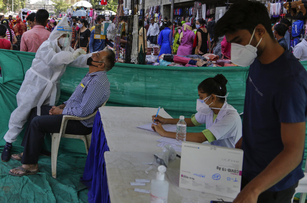 A health worker takes a nasal swab sample of a man to test for COVID-19 at a facility erected in a market in Ahmedabad, India, Tuesday, Nov. 17, 2020. A country of nearly 1.4 billion people, India is the world's second most coronavirus affected country after the United States. (AP Photo/Ajit Solanki)