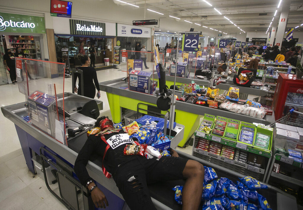 Jonata Anjo lies on a checkout counter at a Carrefour supermarket during a protest against the murder of Black man Joao Alberto Silveira Freitas at a different Carrefour supermarket the night before, on Brazil's National Black Consciousness Day in Rio de Janeiro, Brazil, Friday, Nov. 20, 2020. Freitas died after being beaten by supermarket security guards in the southern Brazilian city of Porto Alegre, sparking outrage as videos of the incident circulated on social media. (AP Photo/Bruna Prado)