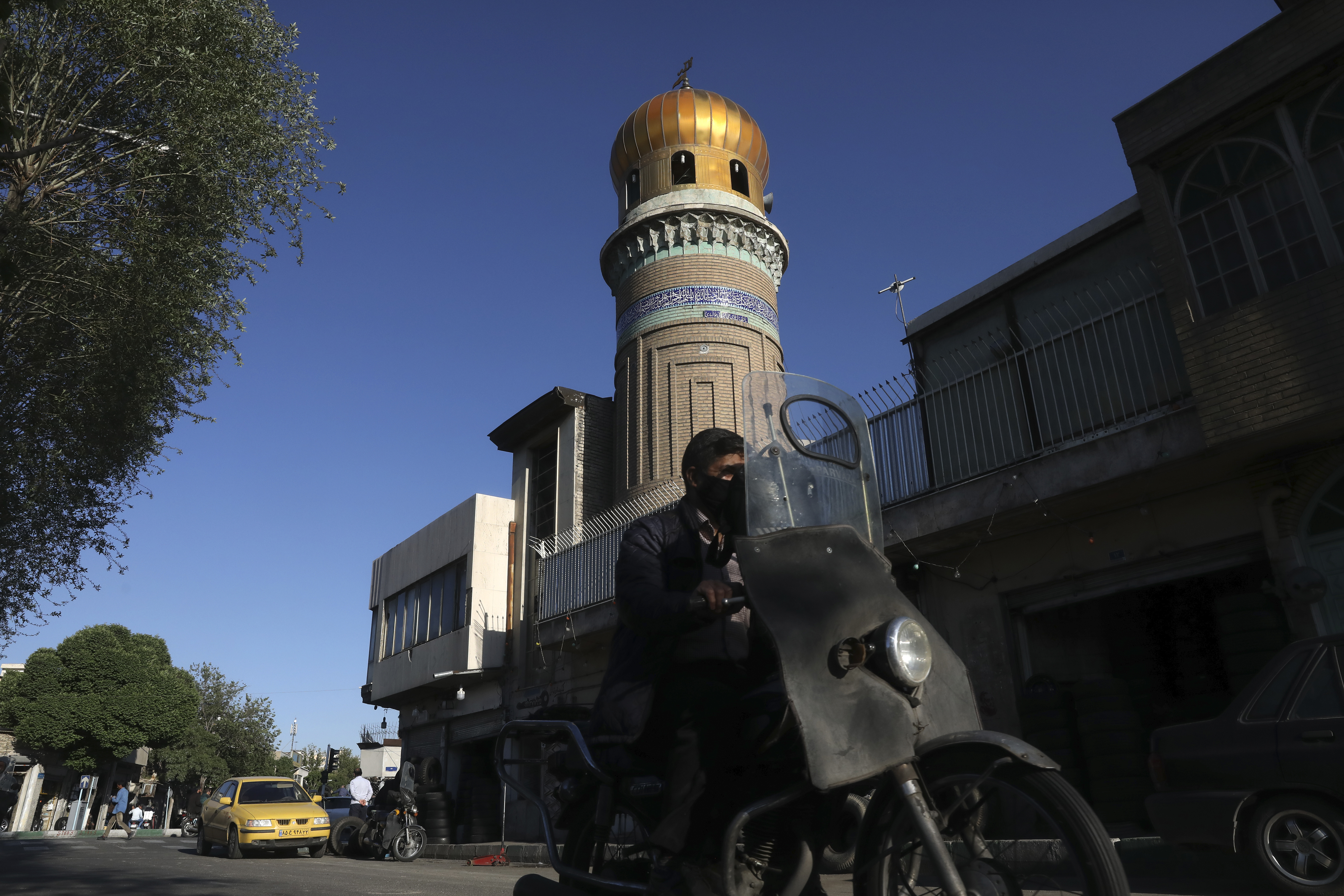 A man drives past a mosque during the Muslim holy fasting month of Ramadan, in southern Tehran, Iran, Monday, April 27, 2020. In Iran, the country that is hit worst in the Middle East by the coronavirus, all religious gathering, congregational prayers and communal Iftar servings, a meal eaten at sunset to break the fast, remain forbidden in the Ramadan and also holy shrines and religious centers also continue to be closed until at least May 4. (AP Photo/Vahid Salemi)
