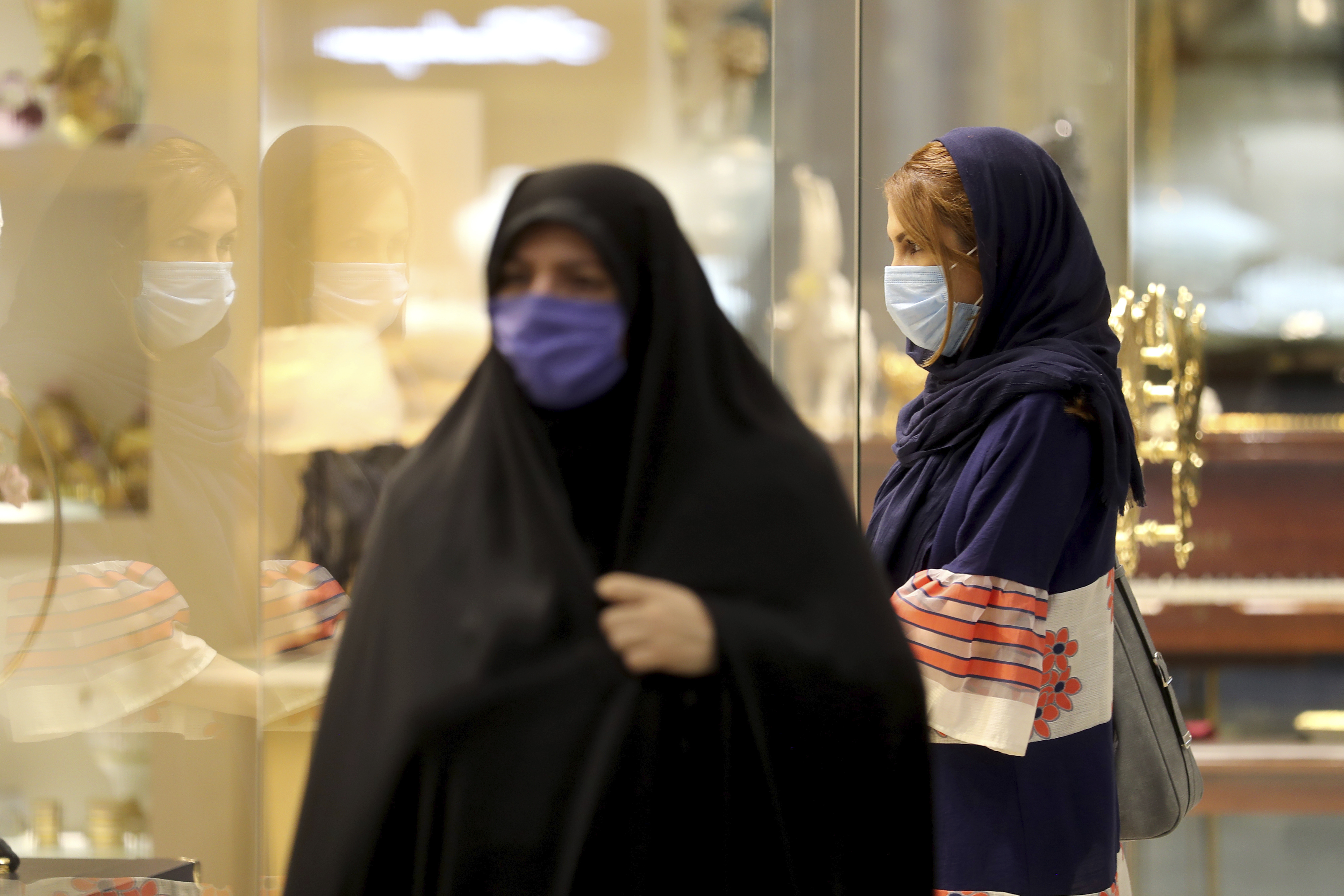 Women wearing protective face masks to help prevent spread of the coronavirus walk through a shopping center, in Tehran, Iran, Wednesday, Aug. 19, 2020. Iran surpassed 20,000 confirmed deaths from the coronavirus on Wednesday, the health ministry said — the highest death toll for any Middle East country so far in the pandemic. (AP Photo/Ebrahim Noroozi)
