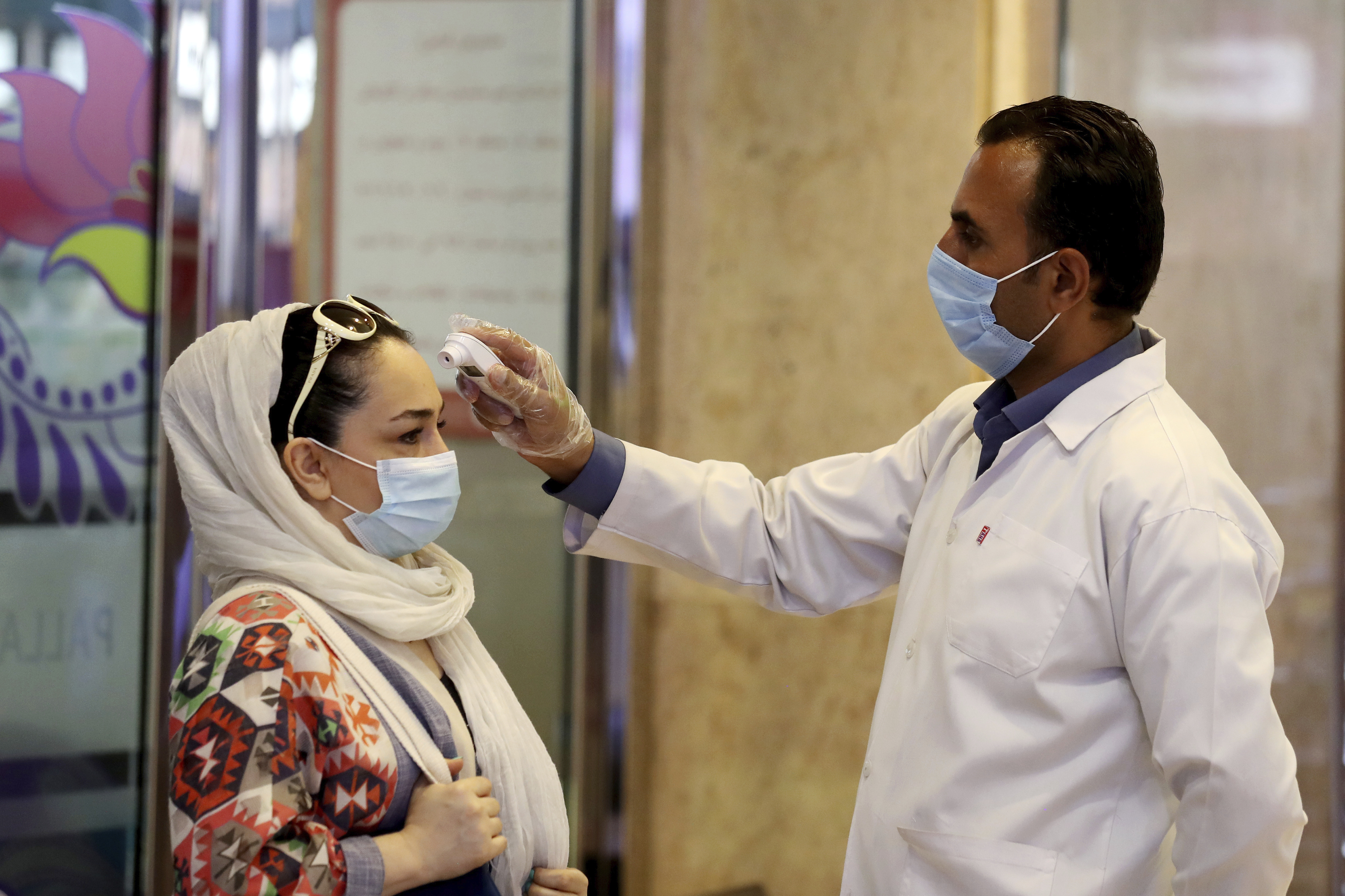 A woman wearing a protective face mask to help prevent spread of the coronavirus has her temperature checked as she enters a shopping center, in Tehran, Iran, Wednesday, Aug. 19, 2020. Iran surpassed 20,000 confirmed deaths from the coronavirus on Wednesday, the health ministry said — the highest death toll for any Middle East country so far in the pandemic. (AP Photo/Ebrahim Noroozi)