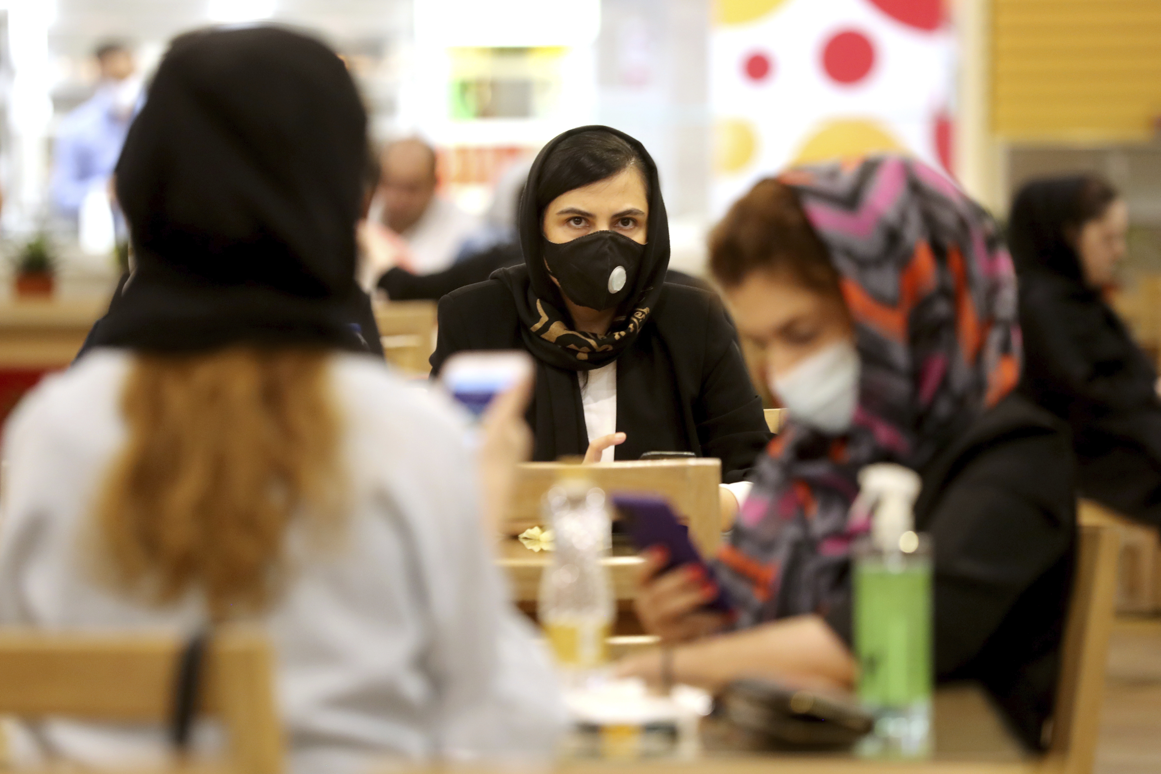 Women wearing protective face masks to help prevent spread of the coronavirus sit at a shopping center food court, in Tehran, Iran, Wednesday, Aug. 19, 2020. Iran surpassed 20,000 confirmed deaths from the coronavirus on Wednesday, the health ministry said — the highest death toll for any Middle East country so far in the pandemic. (AP Photo/Ebrahim Noroozi)