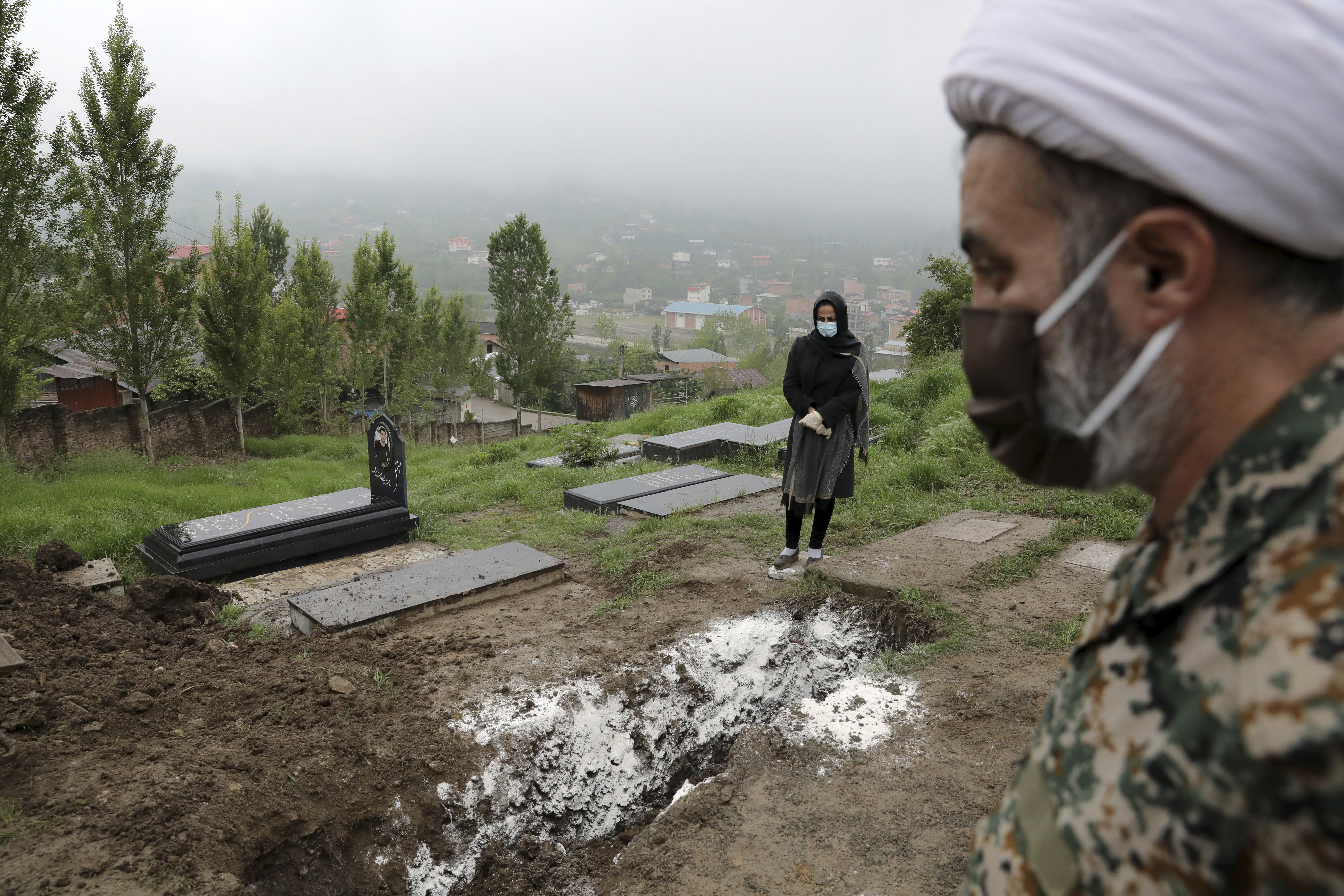FILE - In this April 30, 2020 file photo, a woman wearing mask and gloves, prays at the grave of her mother who died from the new coronavirus, at a cemetery in the outskirts of the city of Babol, in northern Iran. Iranian state TV said Wednesday Oct. 7, 2020, that the country has hit its highest number of daily deaths from the coronavirus, with 239 new fatalities. Wednesday's report quotes the spokesperson of the country’s health ministry as saying the new deaths were recorded since Tuesday. (AP Photo/Ebrahim Noroozi, File)