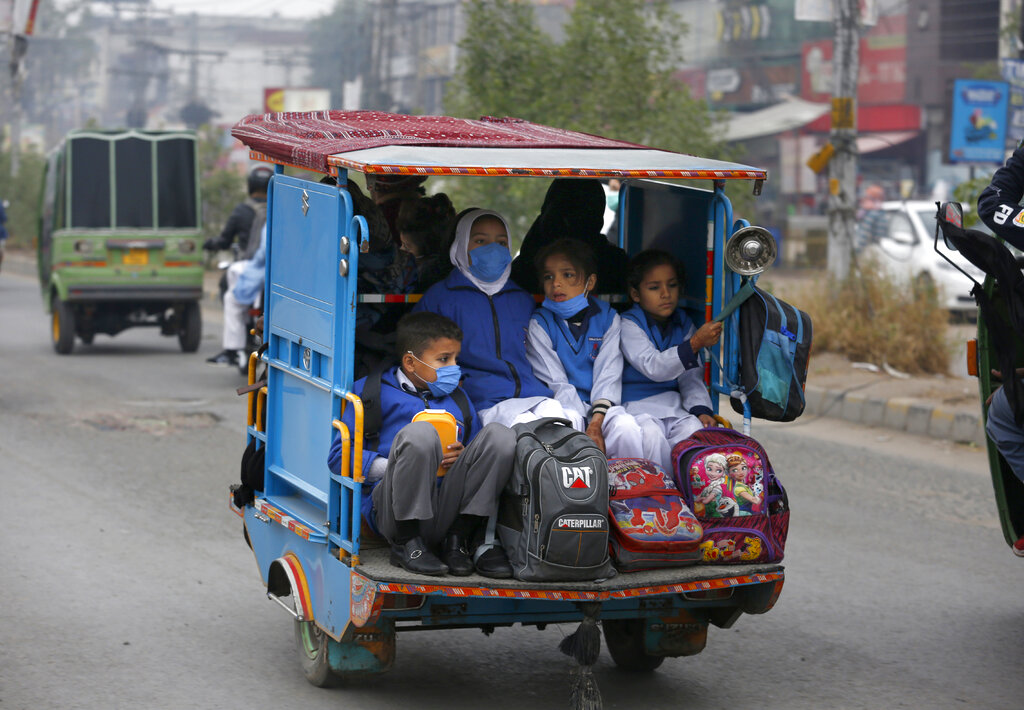 Students wearing face masks to protect against the coronavirus, ride in a tri-wheeler to school in Lahore, Pakistan, Wednesday, Nov. 25, 2020. Pakistan will again close all educational institutions as of Thursday Nov. 26, 2020, because of a steady and increasingly drastic increase in coronavirus cases. (AP Photo/K.M.Chaudary)