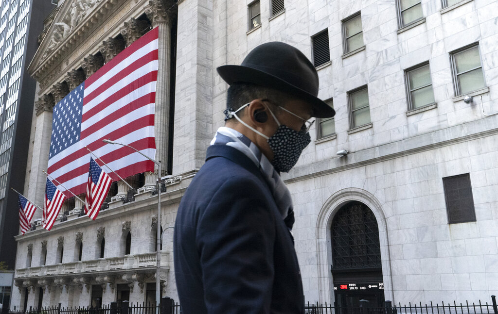 A man wearing a mask passes the New York Stock Exchange, Monday, Nov. 16, 2020, in New York. Stock markets are rallying on news that a second coronavirus vaccine shows promise. (AP Photo/Mark Lennihan)