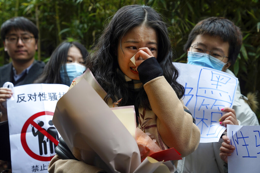 Zhou Xiaoxuan, center, weeps as she speaks to her supporters upon arrival at a courthouse in Beijing, Wednesday, Dec. 2, 2020.  Zhou, a Chinese woman who filed a sexual harassment lawsuit against a TV host, told dozens of cheering supporters at a courthouse Wednesday she hopes her case will encourage other victims of gender violence in a system that gives them few options to pursue complaints. (AP Photo/Andy Wong)