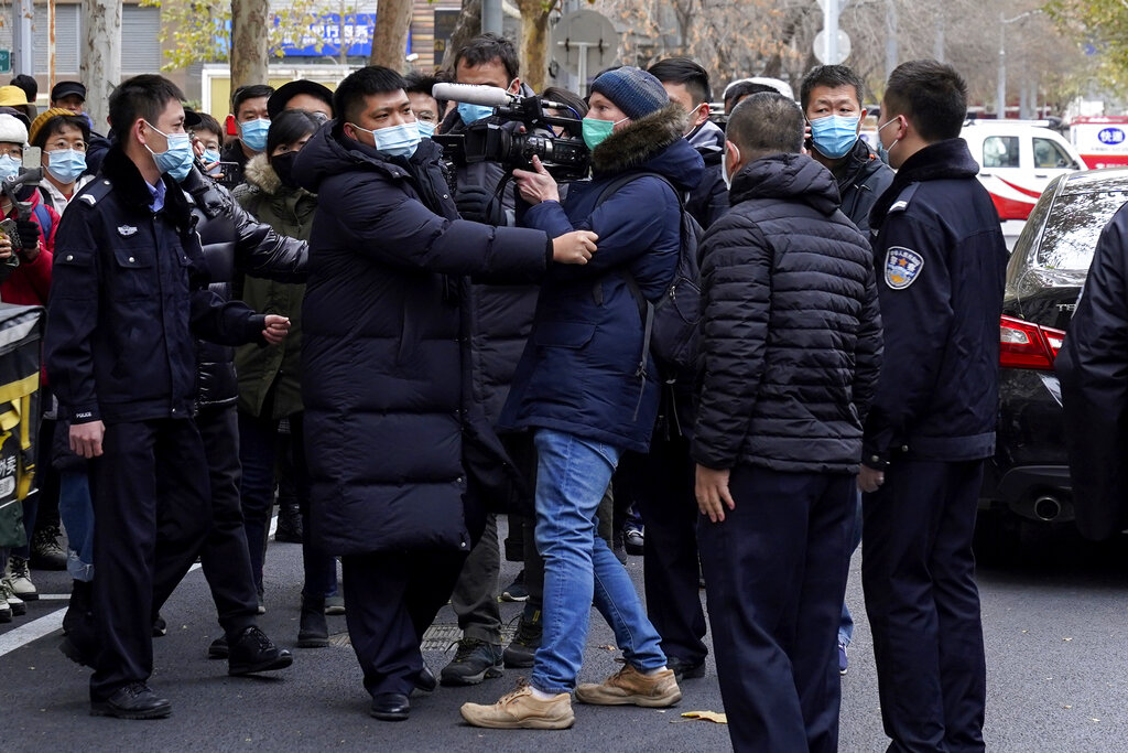 Foreign journalists are stopped by Chinese policemen as they try to film supporters of Zhou Xiaoxuan outside a courthouse in Beijing, Wednesday, Dec. 2, 2020. The Chinese woman who filed a sexual harassment lawsuit against a TV host told cheering supporters at a courthouse Wednesday she hopes her case encourages other 