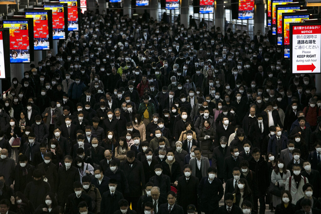 A large crowd wearing masks walks through the Shinagawa Station in Tokyo, Tuesday, March 3, 2020. (AP Photo/Jae C. Hong)