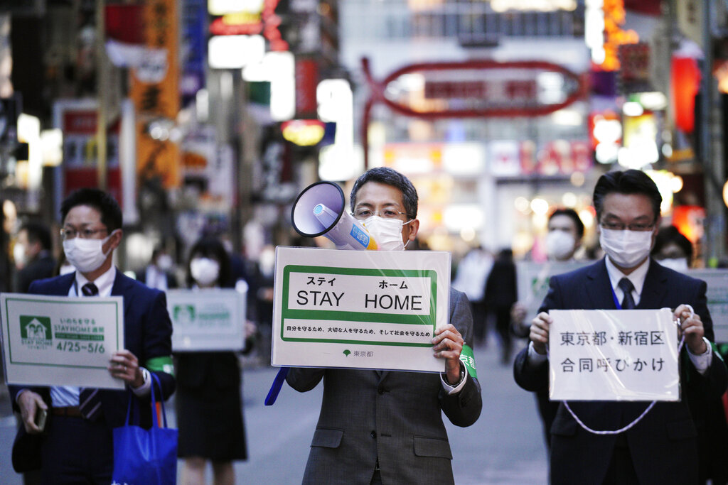 Staff from the Tokyo Metropolitan Government urge people to go home from the Kabukicho entertainment district in the Shinjuku area of Tokyo, Friday evening, April 24, 2020. Japan's Prime Minister Shinzo Abe expanded a state of emergency to all of Japan as the coronavirus spreads. (AP Photo/Eugene Hoshiko)