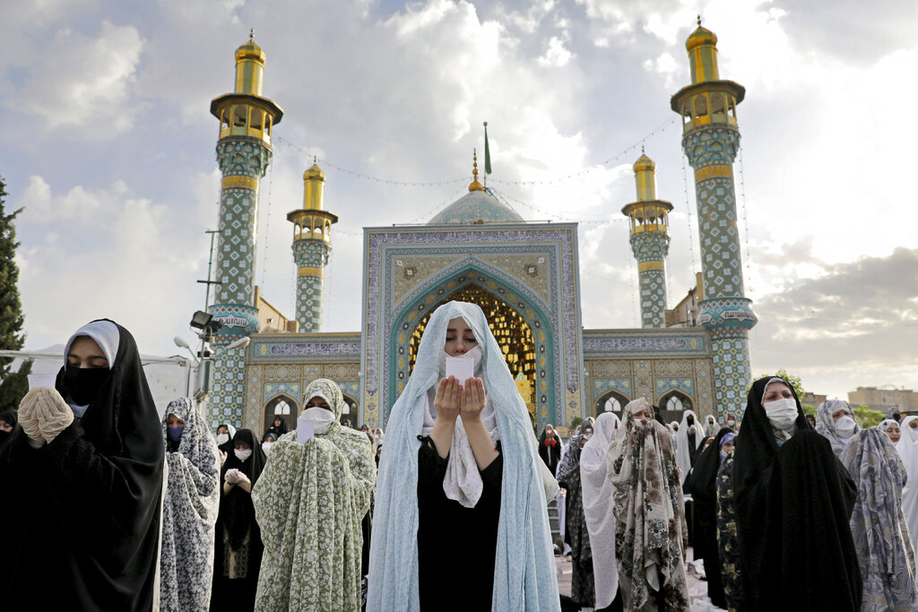 Worshippers wearing protective face masks offer Eid al-Fitr prayers outside a shrine to help prevent the spread of the coronavirus, in Tehran, Iran, Sunday, May 24, 2020. Muslims worldwide celebrated one of their biggest holidays under the long shadow of the coronavirus, with millions confined to their homes and others gripped by economic concerns during what is usually a festive time of shopping and celebration. (AP Photo/Ebrahim Noroozi)