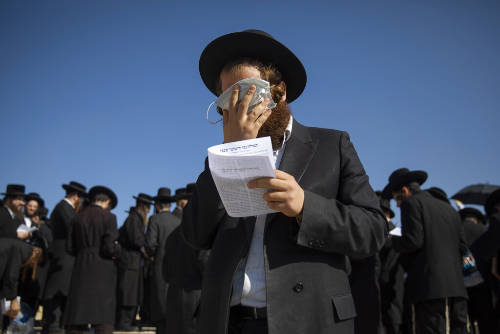 An ultra-Orthodox Jewish man covers his eyes with a face mask during a protest against construction of hotel at a site that protesters claim contains ancient graves, in Jerusalem, on Wednesday, Nov. 18, 2020. (AP Photo/Oded Balilty)