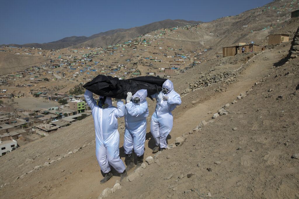 Piedrangel funeral home workers Luis Zerpa, Luis Brito, center, and Jhoan Faneite, right, from Venezuela, carry the body of Marcos Espinoza, 51, who died due to coronavirus, to a hearse in Pachacamac on the outskirts of Lima, Peru, on May 8, 2020. Marcos, single and childless, was an electrician who had changed his trade less than a decade ago after working 25 years as a private security guard. His only brother, Oscar Espinoza, 50, said that hours before he died Marcos lamented that the plague had reached him. 