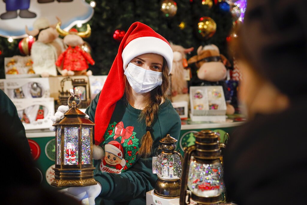 A seller wearing a face mask to help curb the spread of the coronavirus offers Christmas decorations in the Moscow GUM State Department store in Moscow, Russia, Monday, Nov. 23, 2020. New Year is the biggest holiday of the year in Russia, and is followed by the Orthodox Christmas on Jan. 7. Russia, which currently has the world's fifth largest number of confirmed cases, has been swept by a rapid coronavirus resurgence since September. (AP Photo/Alexander Zemlianichenko)
