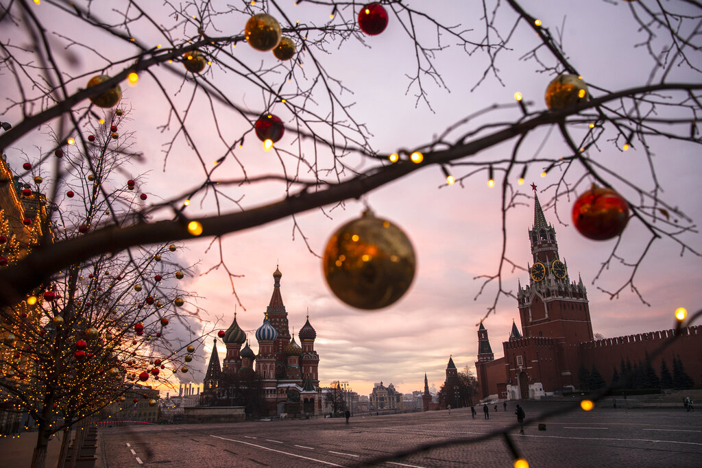 Balls and lights are seen on trees decorated for Christmas and New Year celebrations during a sunrise over Red Square, with St. Basil Cathedral and the Spasskaya Tower, right, in the background in Moscow, Russia, Saturday, Dec. 12, 2020. (AP Photo/Pavel Golovkin)