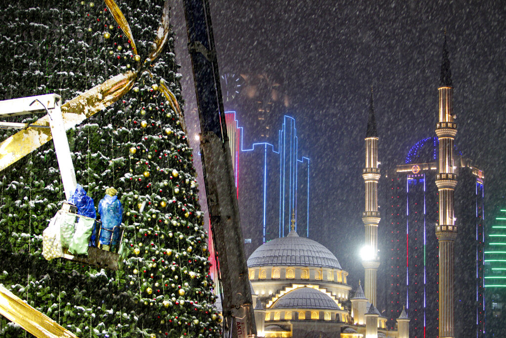 Workers assemble a Christmas tree, with the main Mosque and skyscrapers in the background during a snowfall in downtown Grozny, the capital of Chechnya, in Grozny, Russia, Thursday, Dec. 17, 2020. (AP Photo/Musa Sadulayev)