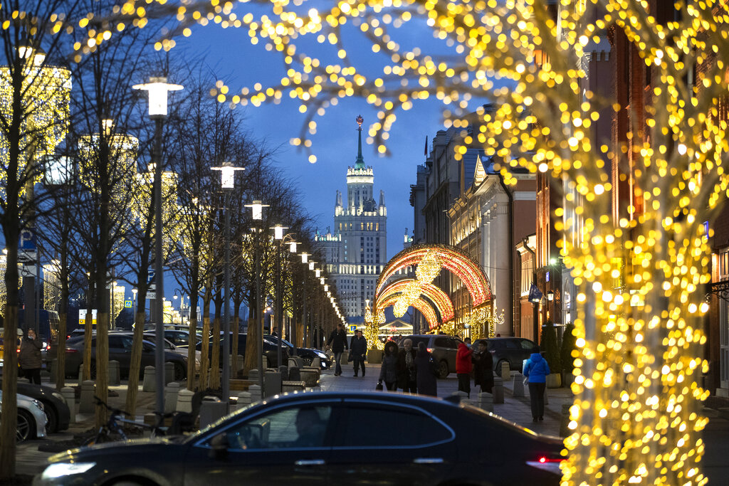 People walk in a street with the Kotelnicheskaya Embankment Building in the background as Russian capital is decorated for New Year celebrations in Moscow, Russia, Monday, Dec. 21, 2020. (AP Photo/Pavel Golovkin)