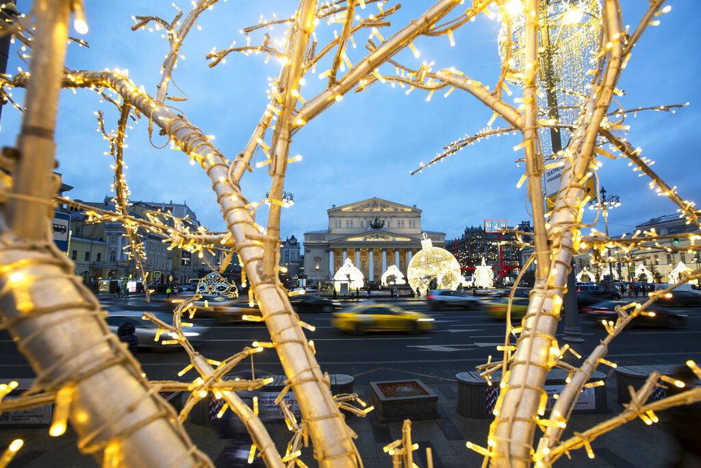 Cars pass the Bolshoi Theatre, in the background, as Russian capital is decorated for New Year celebrations in Moscow, Russia, Monday, Dec. 21, 2020. (AP Photo/Pavel Golovkin)