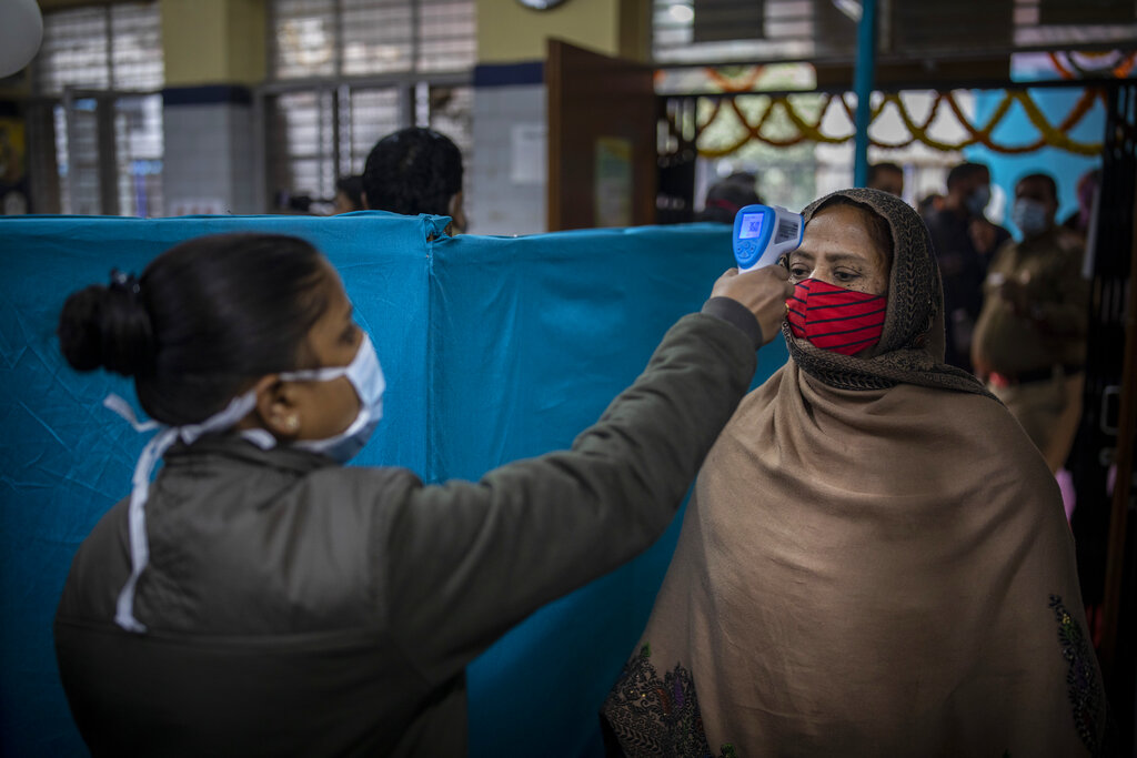 A health worker, left, checks the body temperature of a woman as a precaution against the coronavirus before allowing her to participate in a COVID-19 vaccine delivery system trial in New Delhi, India, Saturday, Jan. 2, 2021. India tested its COVID-19 vaccine delivery system with a nationwide trial on Saturday as it prepares to roll-out an inoculation program to stem the coronavirus pandemic. Saturday’s exercise included necessary data entry into an online platform for monitoring vaccine delivery, along with testing of cold storage and transportation arrangements for the vaccine, the health ministry had said.(AP Photo/Altaf Qadri)