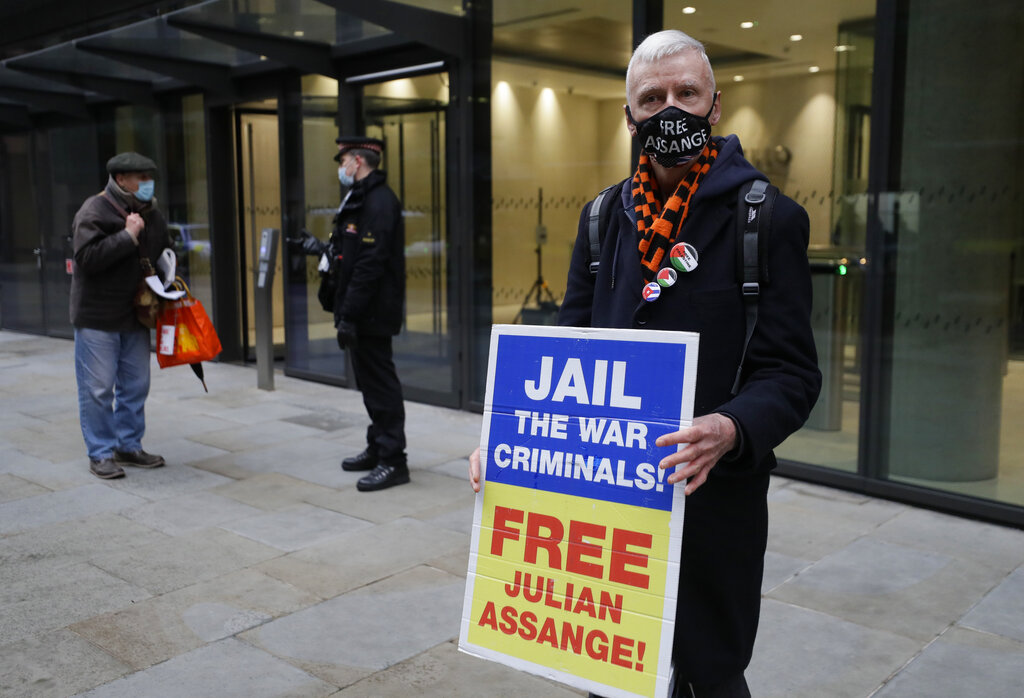 A Julian Assange supporter waits with a placard outside the Old Bailey in London, Monday, Jan. 4, 2021. Judgement is to be made by Judge Vanessa Baraitser on Assange's his extradition hearing to the US. Julian Assange has been charged under the US's 1917 Espionage Act for 