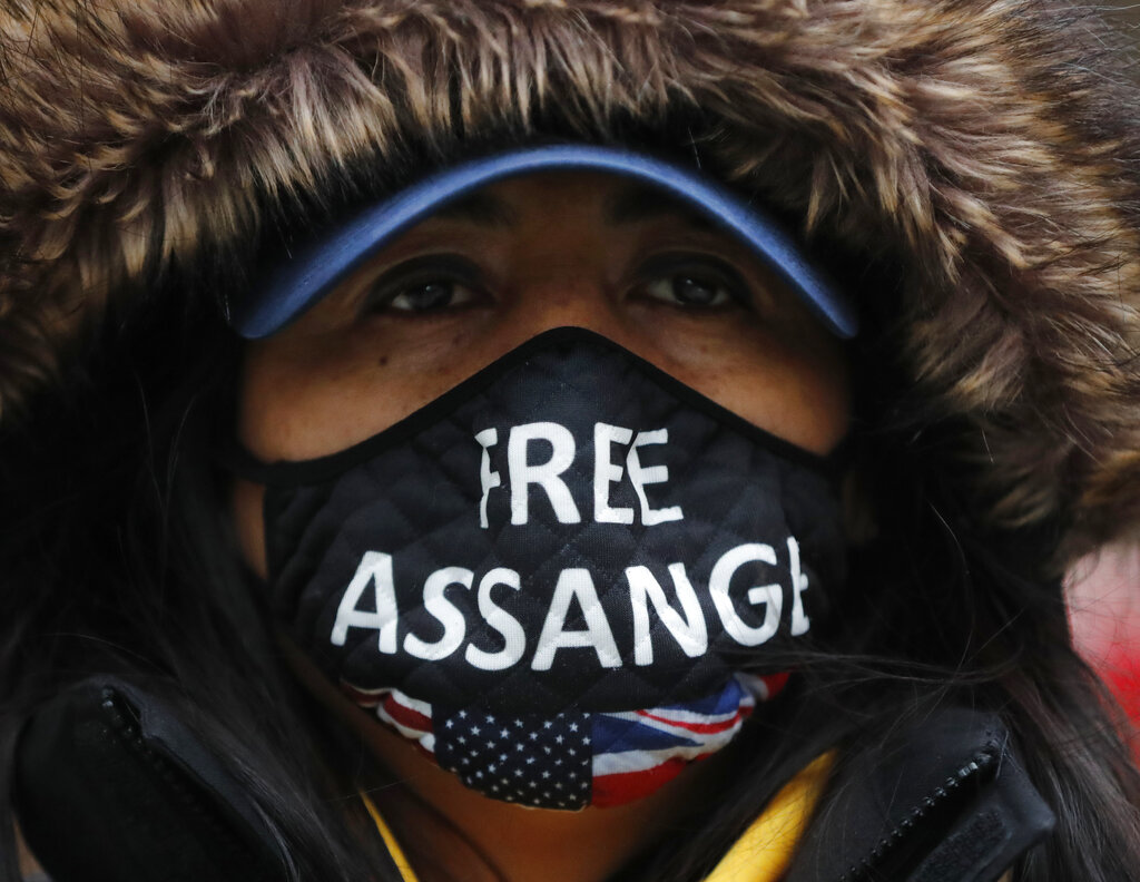 A Julian Assange supporter wears a face mask bearing his name outside the Old Bailey in London, Monday, Jan. 4, 2021. Judgement is to be made by Judge Vanessa Baraitser on Julian Assange's his extradition hearing to the US. Assange has been charged under the US's 1917 Espionage Act for 