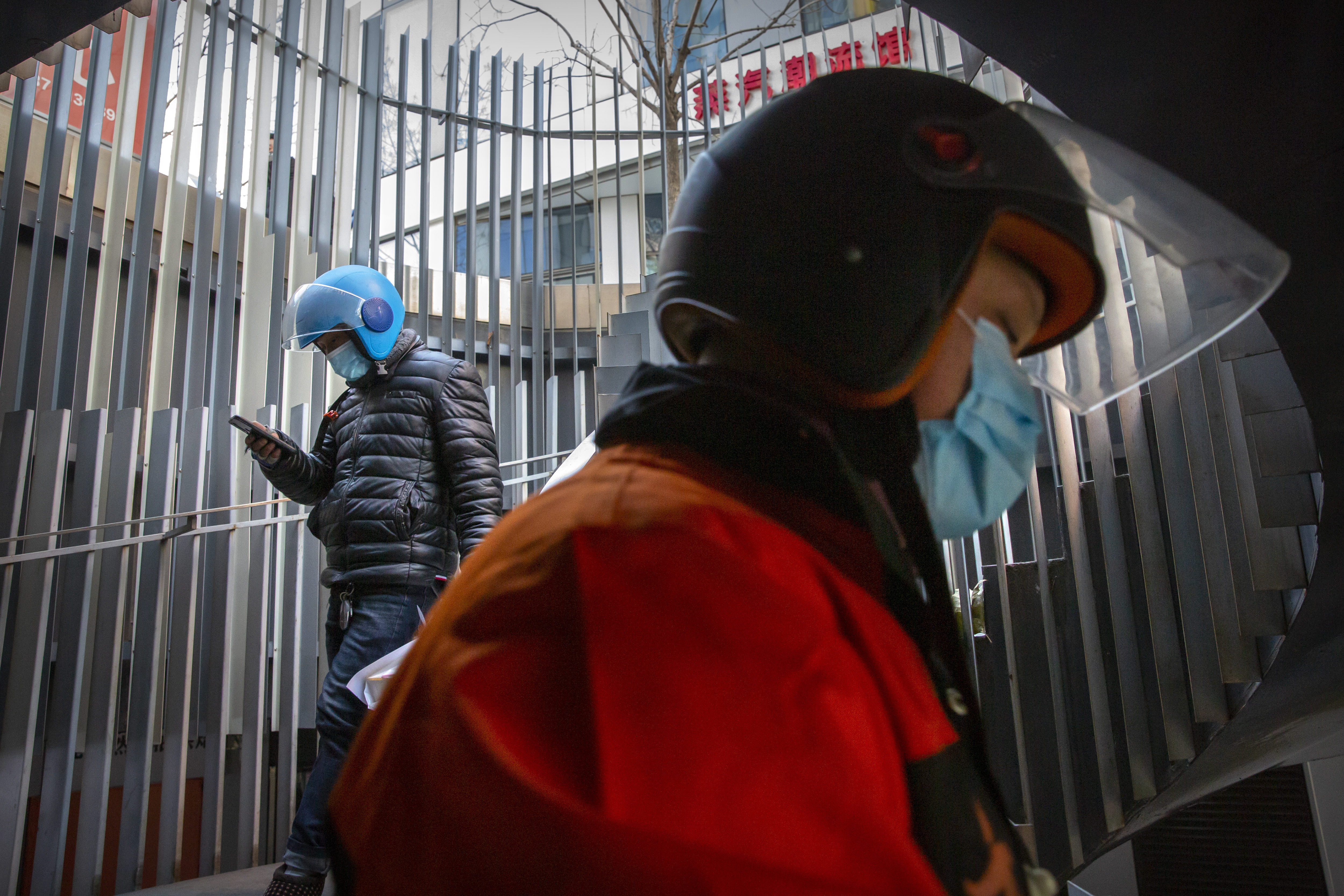 Delivery drivers wearing face masks to protect against the coronavirus walk along a staircase at an office and shopping complex in Beijing, Wednesday, Jan. 6, 2021. China's Hebei province is enforcing stricter control measures following a further rise in coronavirus cases in the province, which is adjacent to the capital Beijing and is due to host events for next year's Winter Olympics. (AP Photo/Mark Schiefelbein)