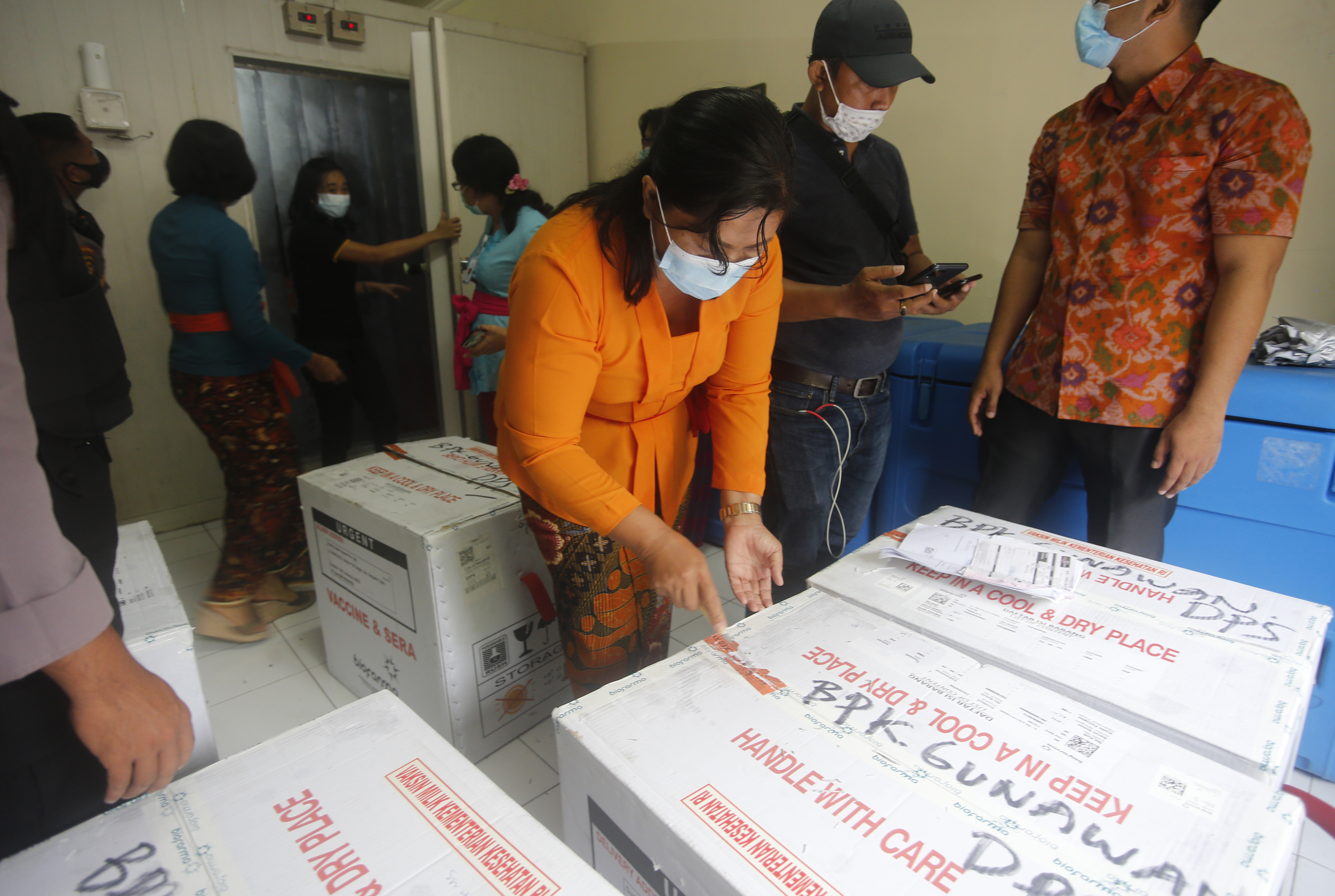 Health workers check the boxes containing coronavirus vaccines developed by China's Sinovac Biotech as they arrived in Bali, Indonesia on Thursday, Jan. 7, 2021. (AP Photo/Firdia Lisnawati)